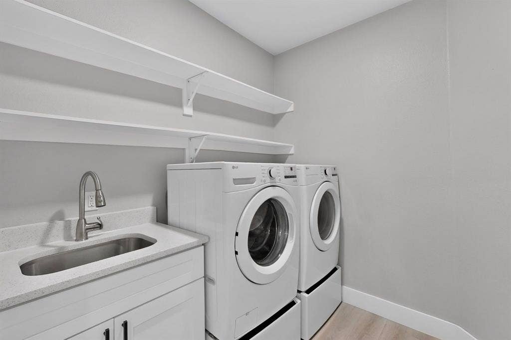 Utility room featuring white cabinetry, a drop-in stainless steel sink, solid surface countertop, high-arc faucet, and multi-tier wall-mounted shelving