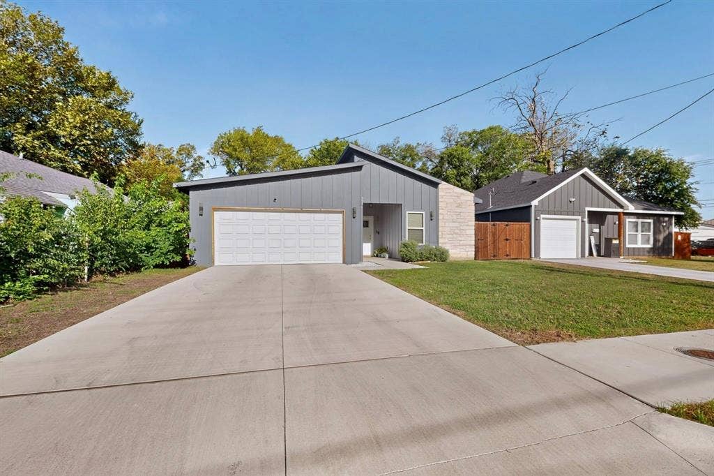 Contemporary exterior featuring vertical metal siding, masonry accents, an attached two-car garage, and a concrete driveway