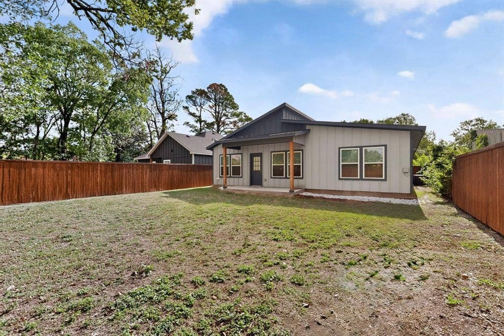 Backyard featuring a vertical siding exterior, covered patio with wood support pillars, and full-perimeter wood fencing