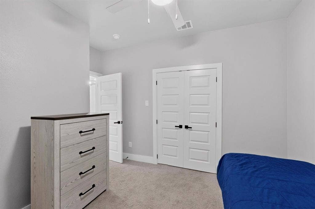 Interior space featuring neutral-toned carpeting, five-panel interior doors with matte black hardware, and an overhead ceiling fan