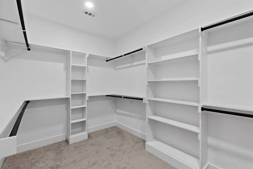Walk-in closet featuring white built-in shelving, vertical storage towers, and black rods