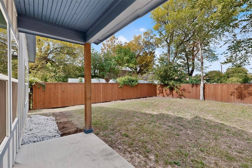 Covered patio featuring a concrete floor and wood-post support, opening to a private backyard enclosed by a horizontal wood fence