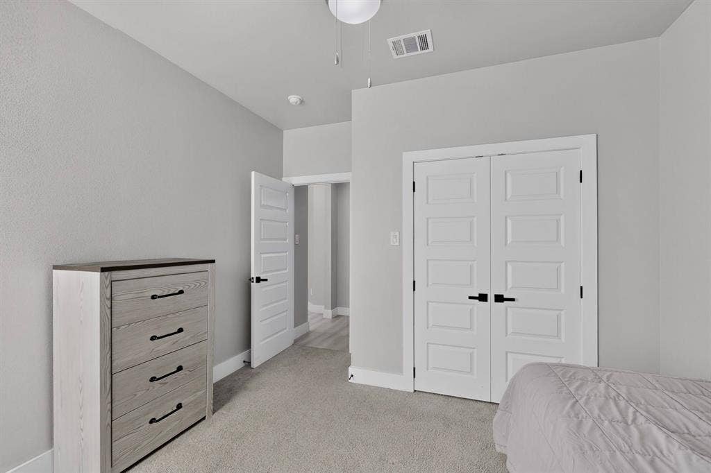 Neutral-toned walls paired with carpeting, featuring two-panel interior doors with matte black hardware and a ceiling-mounted light fixture