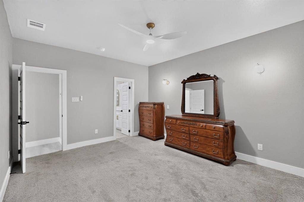 Interior space featuring neutral wall tones, carpeted flooring, a contemporary multi-blade ceiling fan, and wall-mounted light fixtures