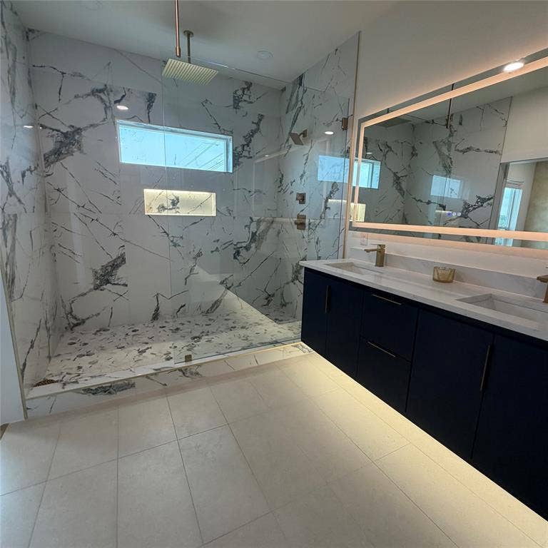 Floating vanity featuring dark cabinetry, dual integrated sinks, and under-cabinet lighting