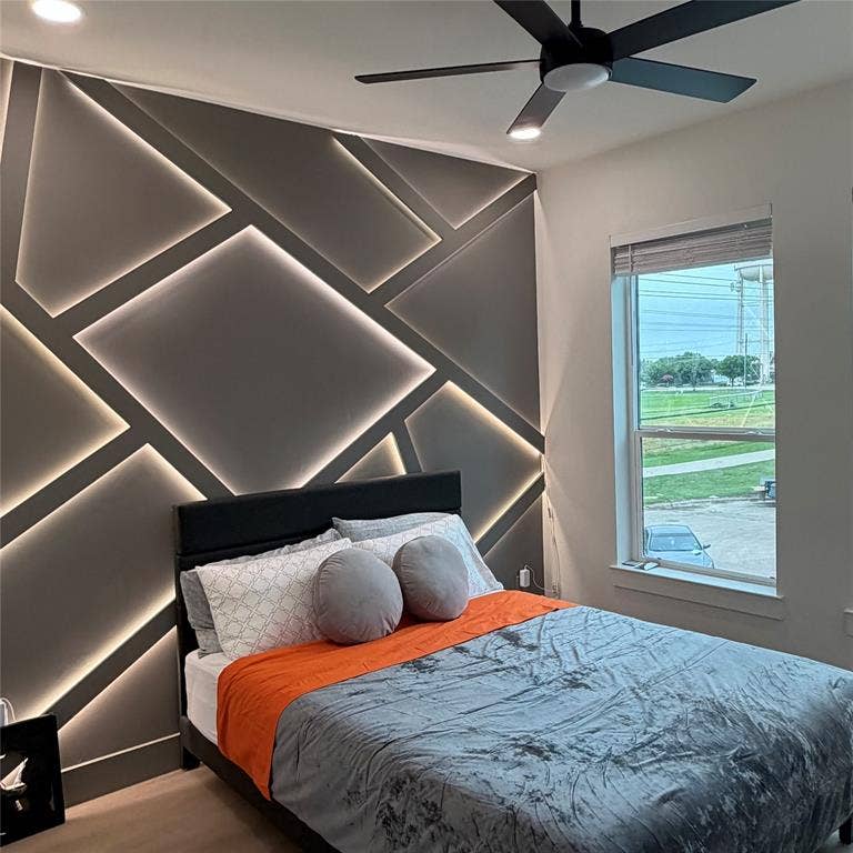Custom accent wall featuring geometric paneling with integrated recessed lighting, recessed ceiling lighting, and a modern matte black ceiling fan