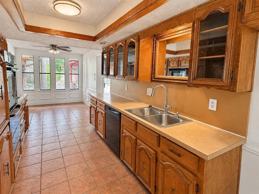 1444 Marlene Place, DeSoto, TX 75115 Kitchen featuring wood cabinetry, a double basin stainless steel sink with a gooseneck faucet, light-toned countertops, and tile flooring