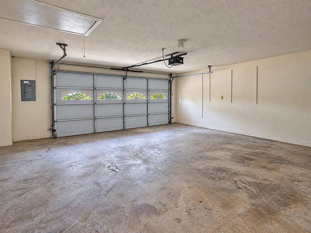 1444 Marlene Place, DeSoto, TX 75115 Attached garage featuring a sectional door with frosted arched window inserts, concrete flooring, and an overhead access panel