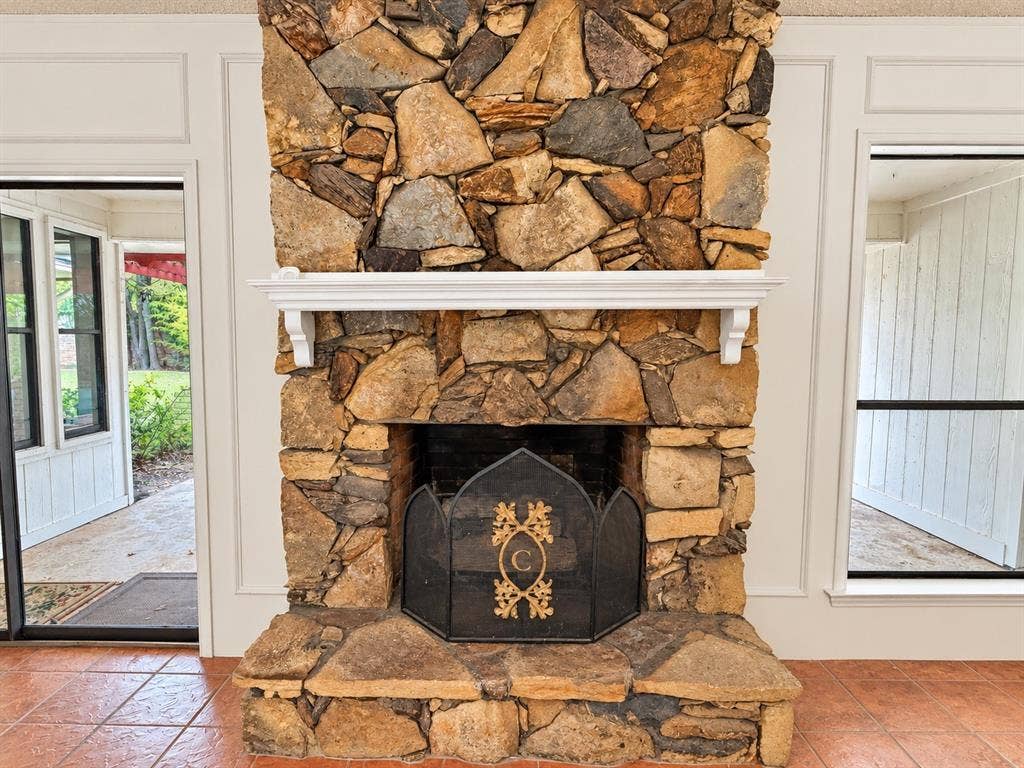 1444 Marlene Place, DeSoto, TX 75115 Natural stone fireplace with a white mantel, terracotta floor tiles, and panel molding trim