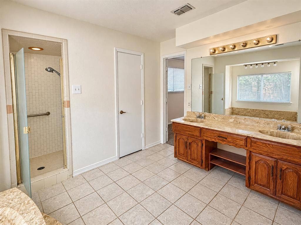 1444 Marlene Place, DeSoto, TX 75115 Dual vanity with integrated sinks and a stone countertop, individual mirrors, a shower enclosure with a glass door, and tiled flooring