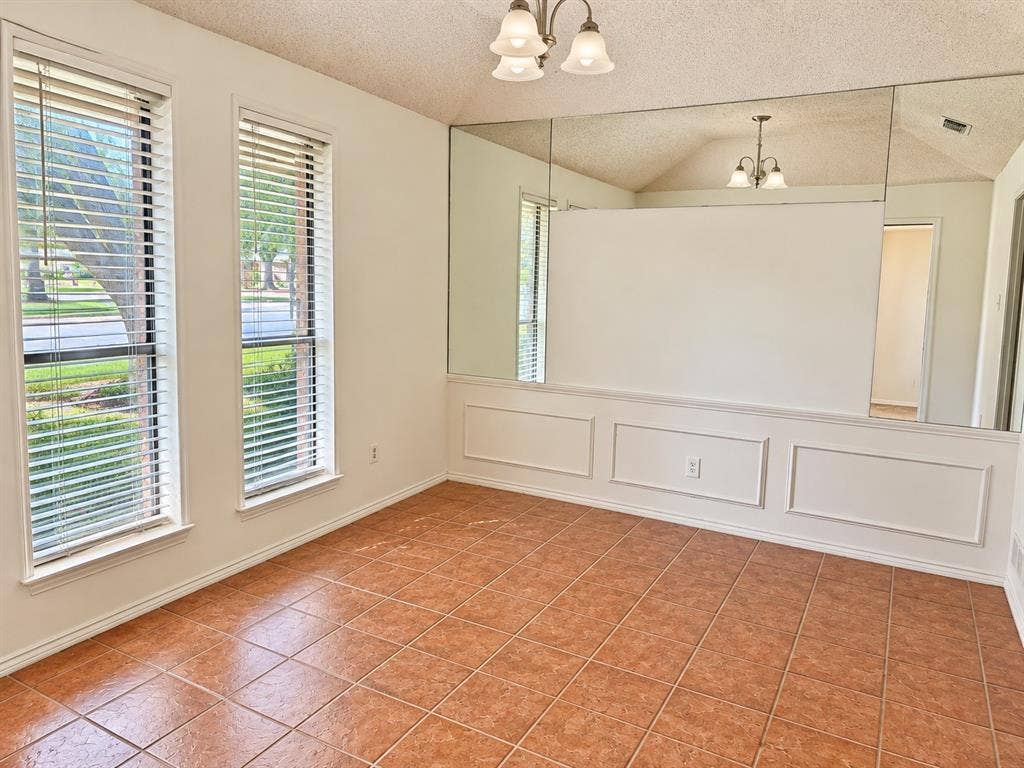 1444 Marlene Place, DeSoto, TX 75115 Terracotta-style tile flooring, two window openings with blinds, decorative wall molding, full-height wall mirror, and a ceiling-mounted light fixture