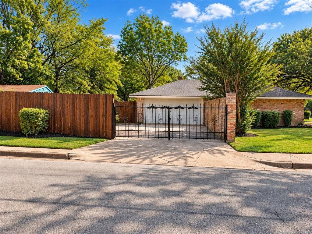 1444 Marlene Place, DeSoto, TX 75115 Wrought iron gate with brick pillars, leading to an attached garage with a decorative door