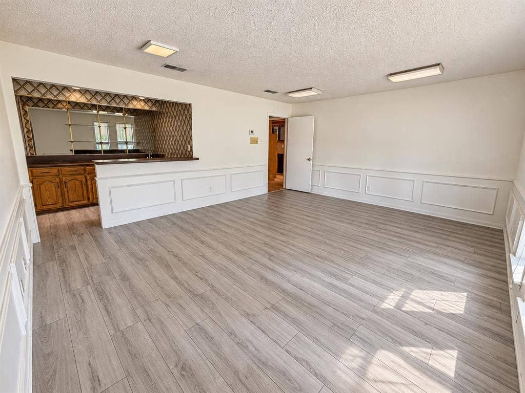 1444 Marlene Place, DeSoto, TX 75115 Wood-finish flooring, wainscoting, built-in wet bar with wood cabinetry, mirrored backsplash, and overhead lighting fixtures