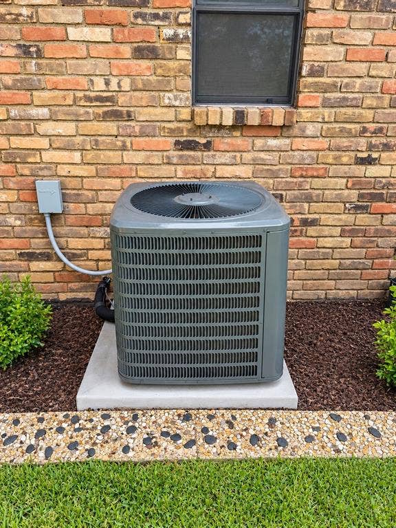 1444 Marlene Place, DeSoto, TX 75115 Brick exterior with a window, air conditioning unit on a concrete pad, decorative stone border, and landscaping