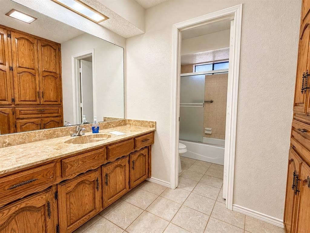 1444 Marlene Place, DeSoto, TX 75115 Extended vanity featuring an integrated sink with a polished chrome faucet, substantial mirror, and wood-finish cabinetry