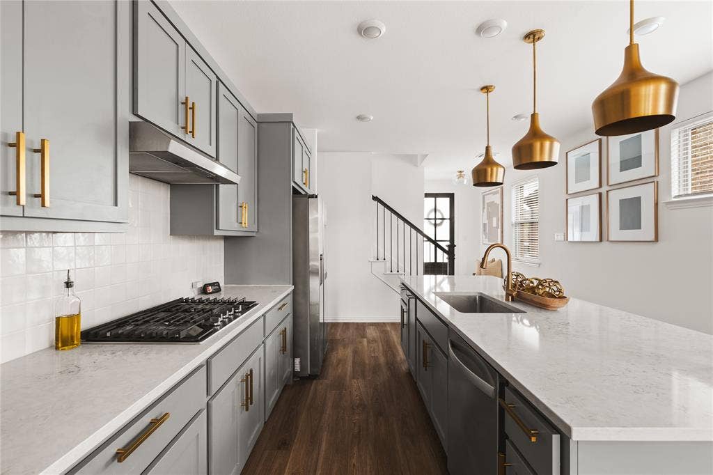 1456 Martingale Lane, Forney, TX 75126 Kitchen featuring shaker-style cabinetry with brass-finish hardware, quartz countertops, a white tile backsplash, metal pendant lighting, and wood-finish flooring
