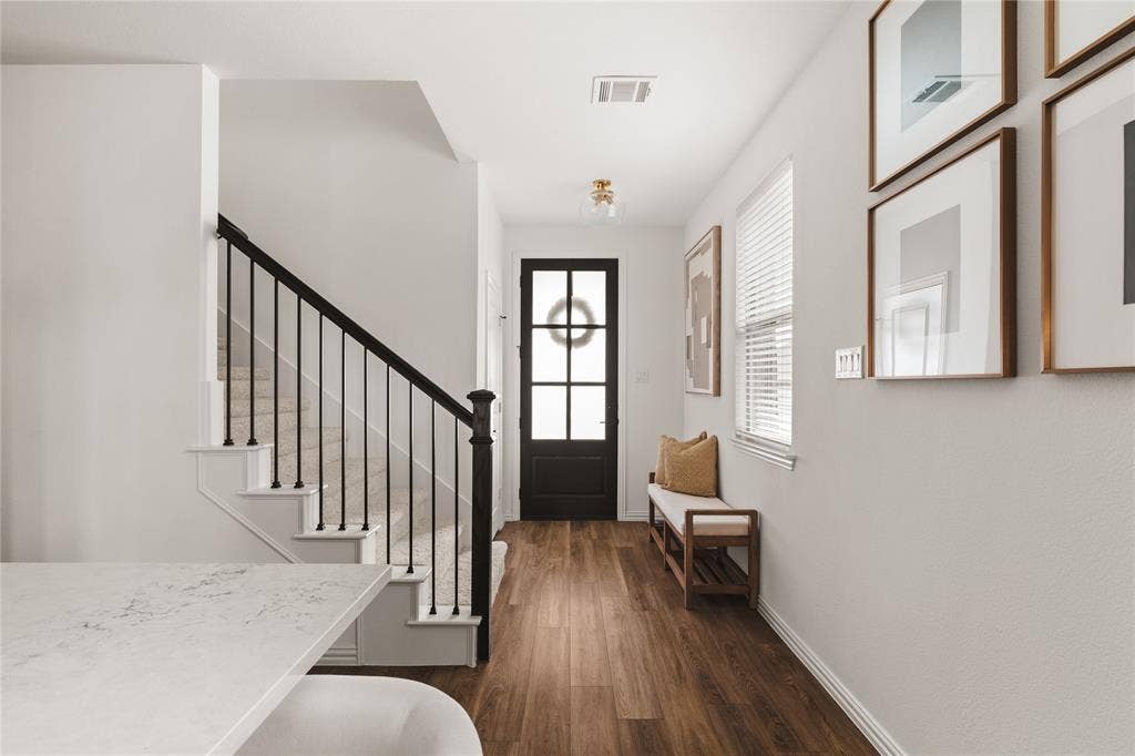 1456 Martingale Lane, Forney, TX 75126 Entryway featuring wood-finish flooring, staircase with a matte black metal railing, glass-paneled entry door, and flush-mount brass light fixture