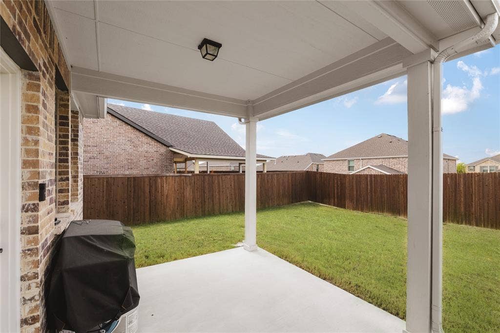1456 Martingale Lane, Forney, TX 75126 Covered concrete patio featuring a brick exterior wall, solid wood fencing, and a built-in ceiling light fixture