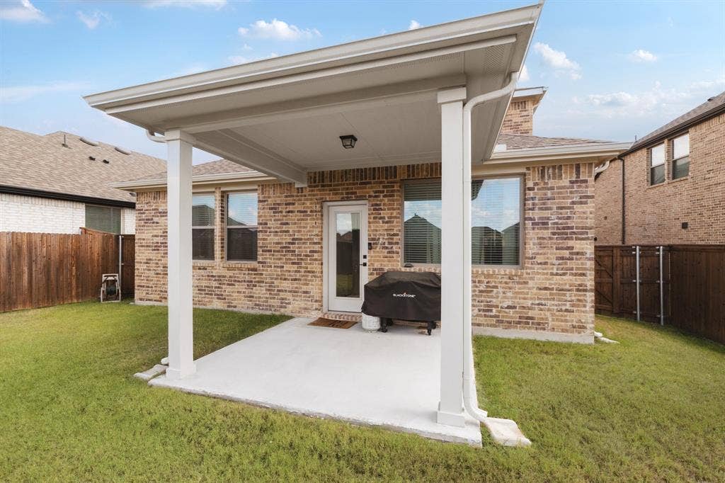 1456 Martingale Lane, Forney, TX 75126 Covered patio featuring a concrete slab, brick exterior cladding, and wood-fence perimeter