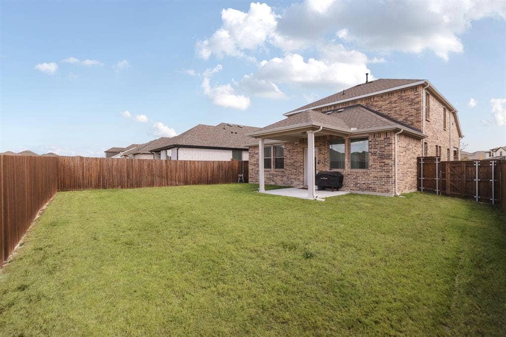 1456 Martingale Lane, Forney, TX 75126 Brick exterior, covered rear patio, and enclosed backyard with wood fencing