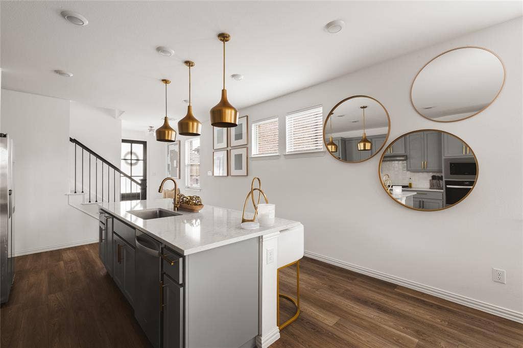 1456 Martingale Lane, Forney, TX 75126 Kitchen island featuring light-toned stone-finish countertop, dual-tone cabinetry, recessed lighting, wood-finish flooring, and metallic pendant fixtures