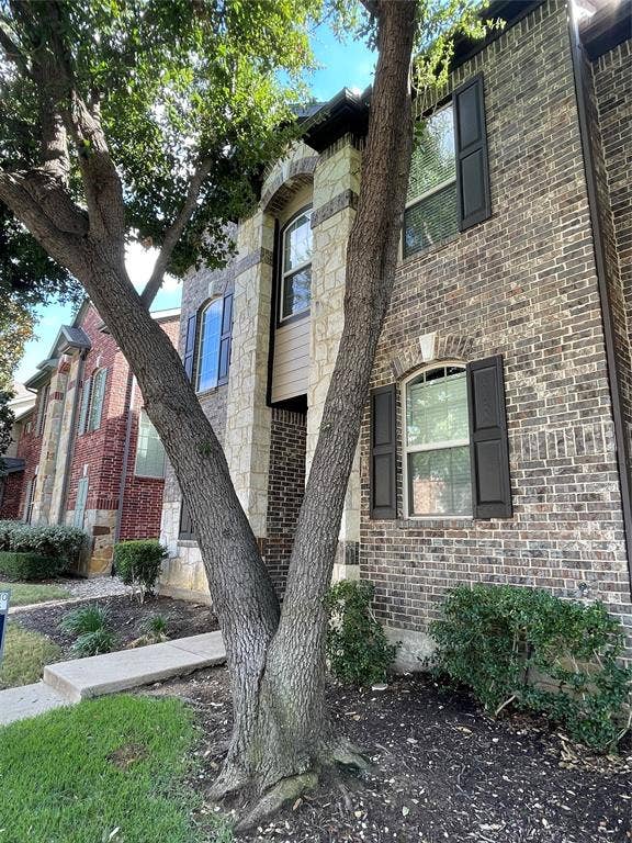 1944 Loma Linda Drive, Irving, TX 75063 Multi-story exterior featuring a brick and stone facade, arched windows with dark shutters, and a concrete walkway