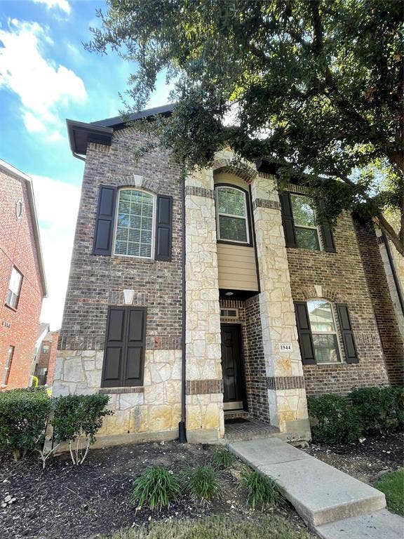 1944 Loma Linda Drive, Irving, TX 75063 Two-story exterior featuring a mix of brick and natural stone masonry, arched window detailing, dark shutters, and a concrete walkway