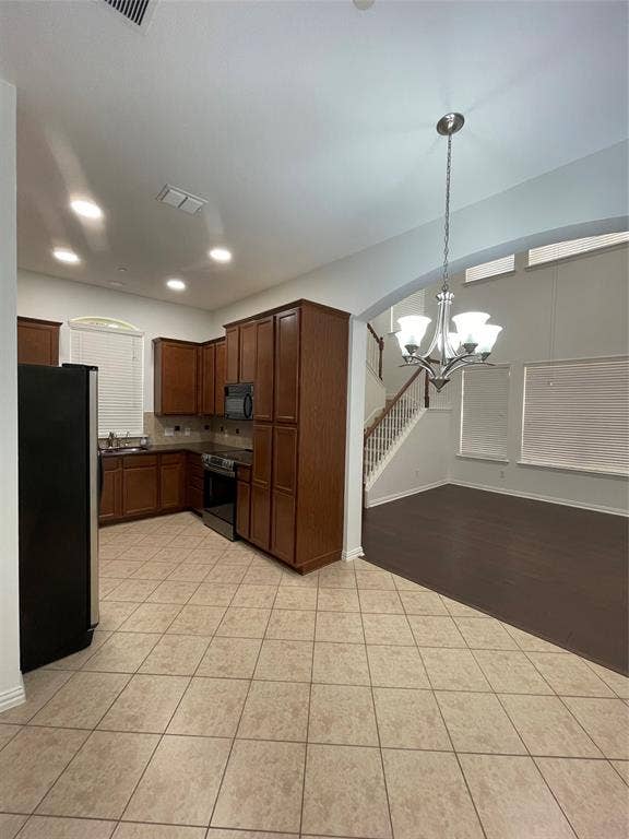 1944 Loma Linda Drive, Irving, TX 75063 Kitchen featuring wood cabinetry, tile flooring, recessed lighting, and a multi-arm pendant light, with wood-finish flooring in the high-ceilinged space