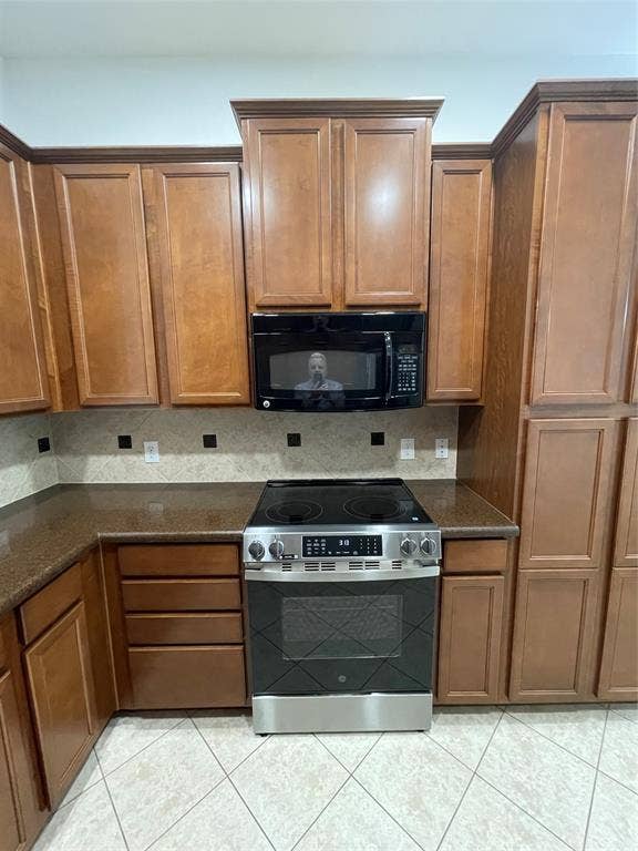 1944 Loma Linda Drive, Irving, TX 75063 Stained wood cabinetry, stone-surface countertops, built-in black microwave, stainless steel electric range, and diagonal tile flooring