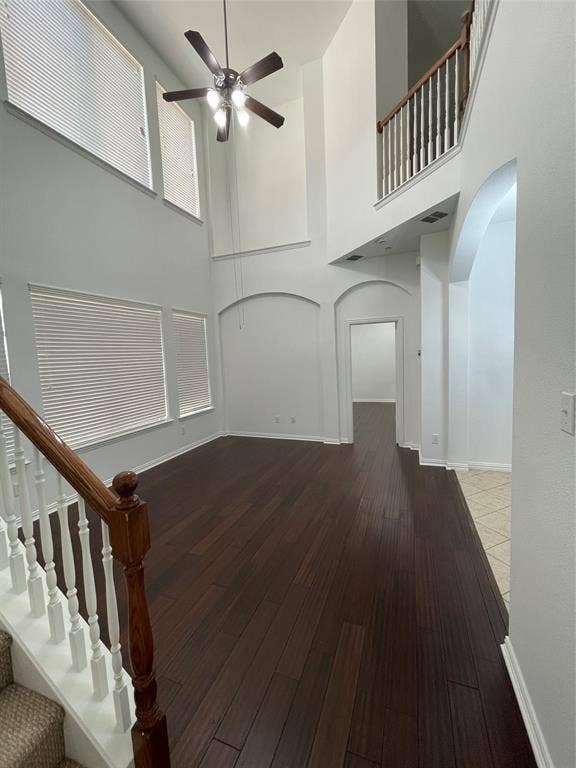 1944 Loma Linda Drive, Irving, TX 75063 High-ceiling interior featuring wood-finish flooring, architectural wall arches, multiple windows, and a staircase with a wooden handrail and white balusters