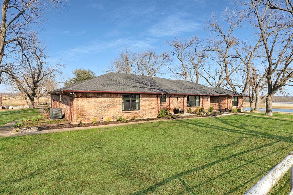 9259 County Road 578, Anna, TX 75409 Single-story brick exterior featuring a hipped roof, dark-trimmed windows, and expansive lawn space