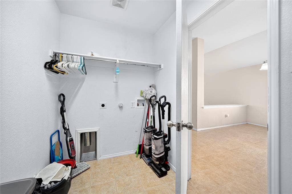 8448 Little Fawn Lane, Dallas, TX 75249 Dedicated utility area featuring tile flooring, built-in shelving, and washer and dryer hookups