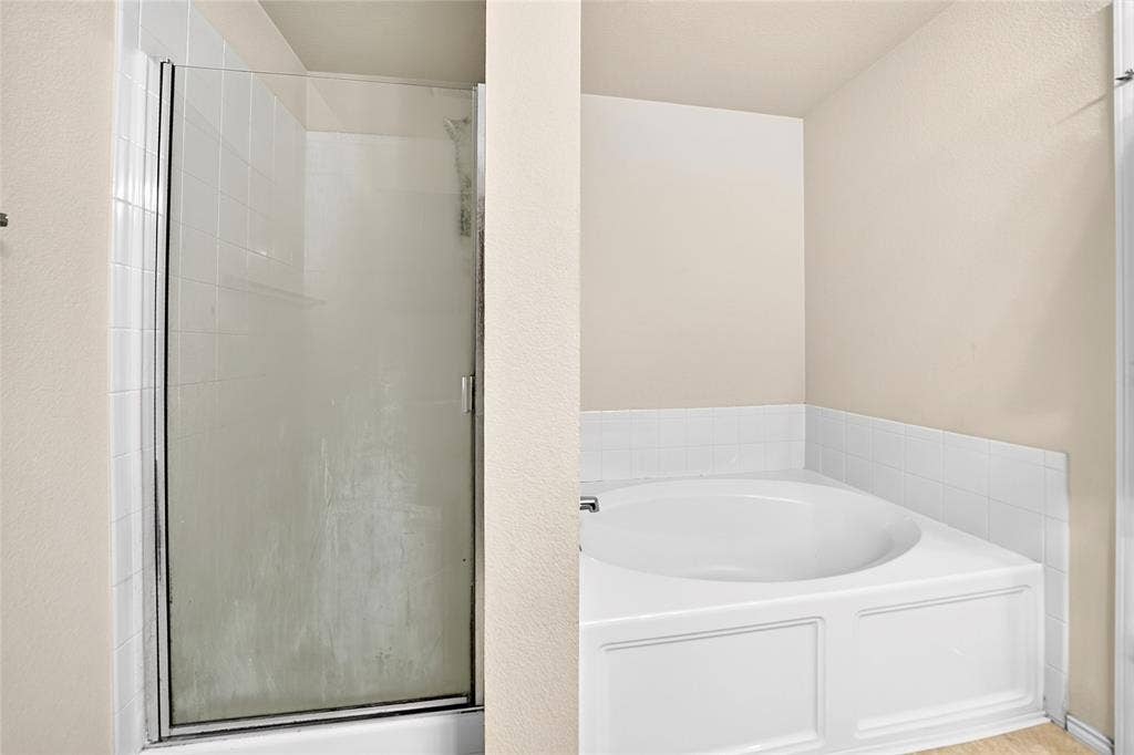 8448 Little Fawn Lane, Dallas, TX 75249 Separate stall shower with glass enclosure and built-in deep soaking tub with white tile surround