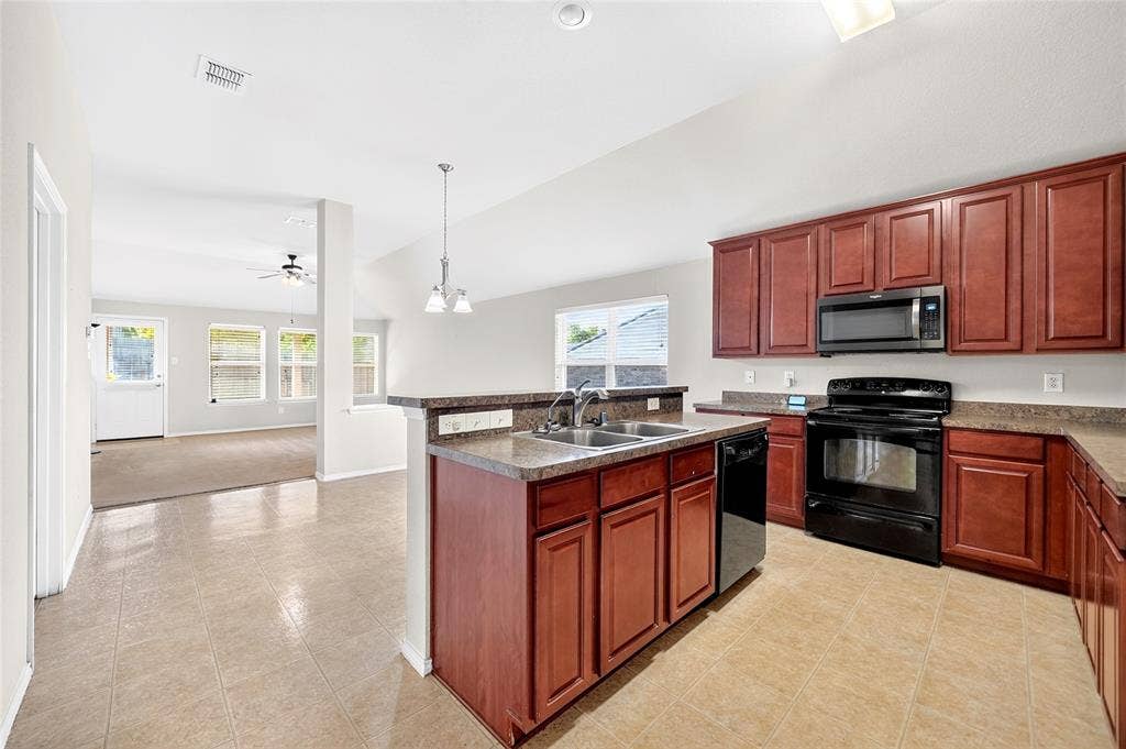 8448 Little Fawn Lane, Dallas, TX 75249 Kitchen featuring wood-finish cabinetry, stone-texture laminate countertops, dual-basin stainless steel sink, black built-in appliances, and ceramic tile flooring