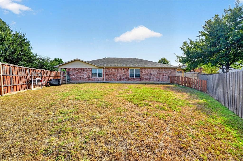 8448 Little Fawn Lane, Dallas, TX 75249 Private backyard featuring brick exterior cladding, a hipped roof, and full wood-plank fencing