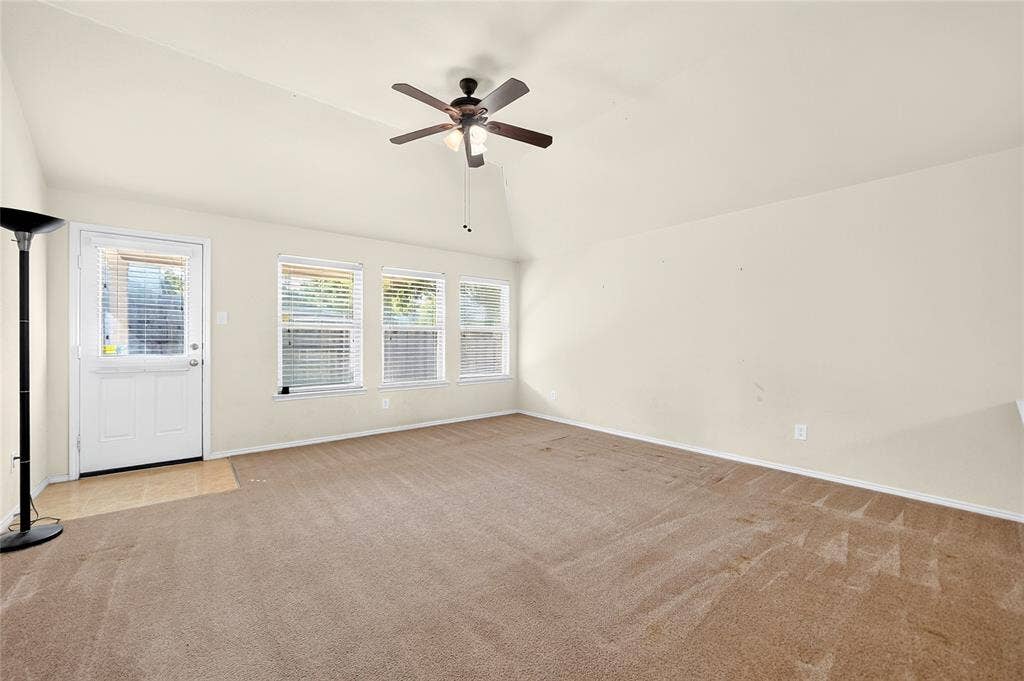 8448 Little Fawn Lane, Dallas, TX 75249 Vaulted ceilings featuring a central ceiling fan, neutral wall finishes, carpeted flooring, and three windows providing natural light