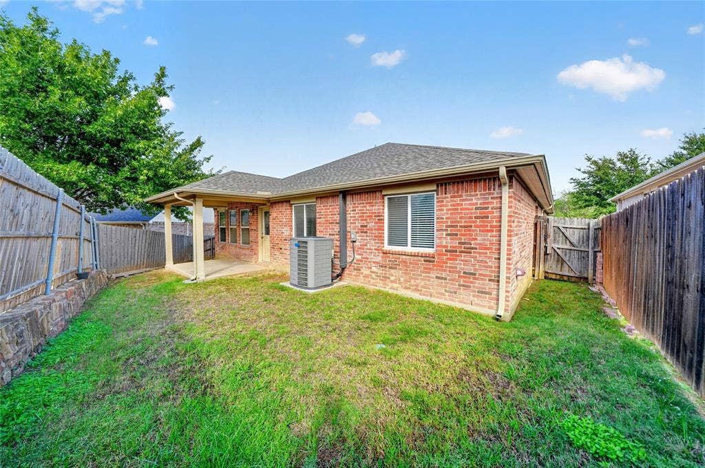 8448 Little Fawn Lane, Dallas, TX 75249 Rear exterior featuring red brick masonry, a covered patio, and wood privacy fencing