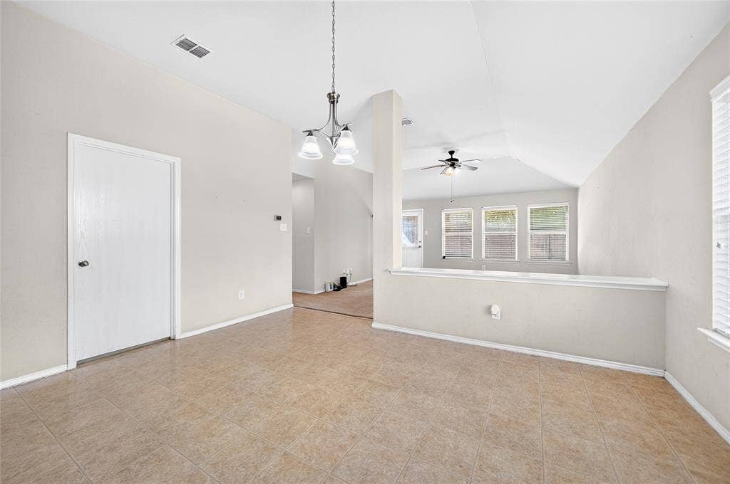 8448 Little Fawn Lane, Dallas, TX 75249 Interior space featuring ceramic tile flooring, vaulted ceilings, a decorative multi-light chandelier, a ceiling fan with integrated lighting, and a half-wall partition