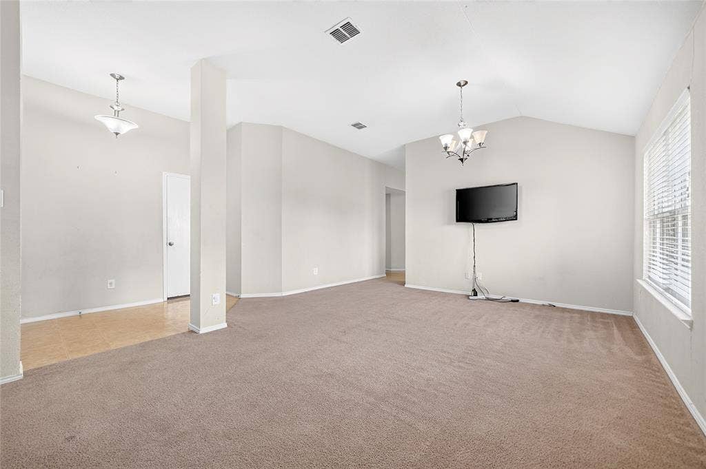 8448 Little Fawn Lane, Dallas, TX 75249 Open interior space featuring vaulted ceilings, neutral wall tones, multi-light chandeliers, and neutral wall-to-wall carpeting
