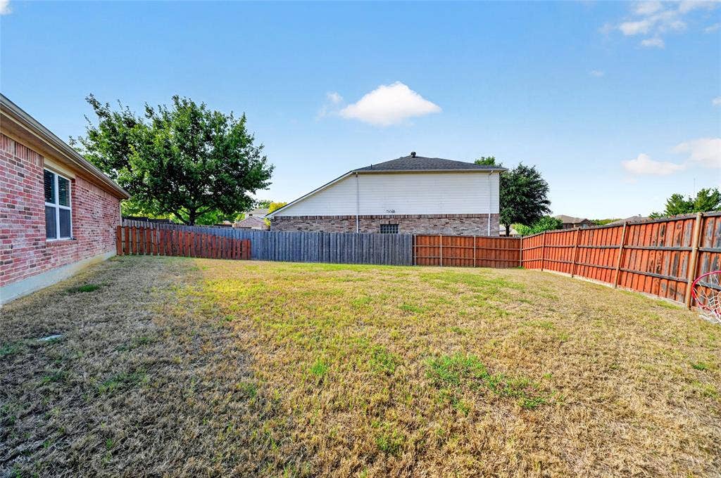 8448 Little Fawn Lane, Dallas, TX 75249 Backyard featuring a red brick exterior wall, full-perimeter wood fencing, and mature trees