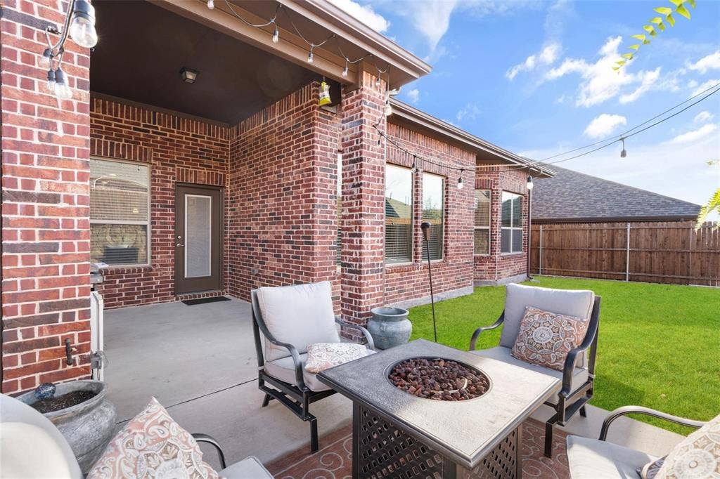 1017 Hoyt Drive, McKinney, TX 75071 Covered concrete patio featuring brick columns, exterior brick siding, and multiple windows