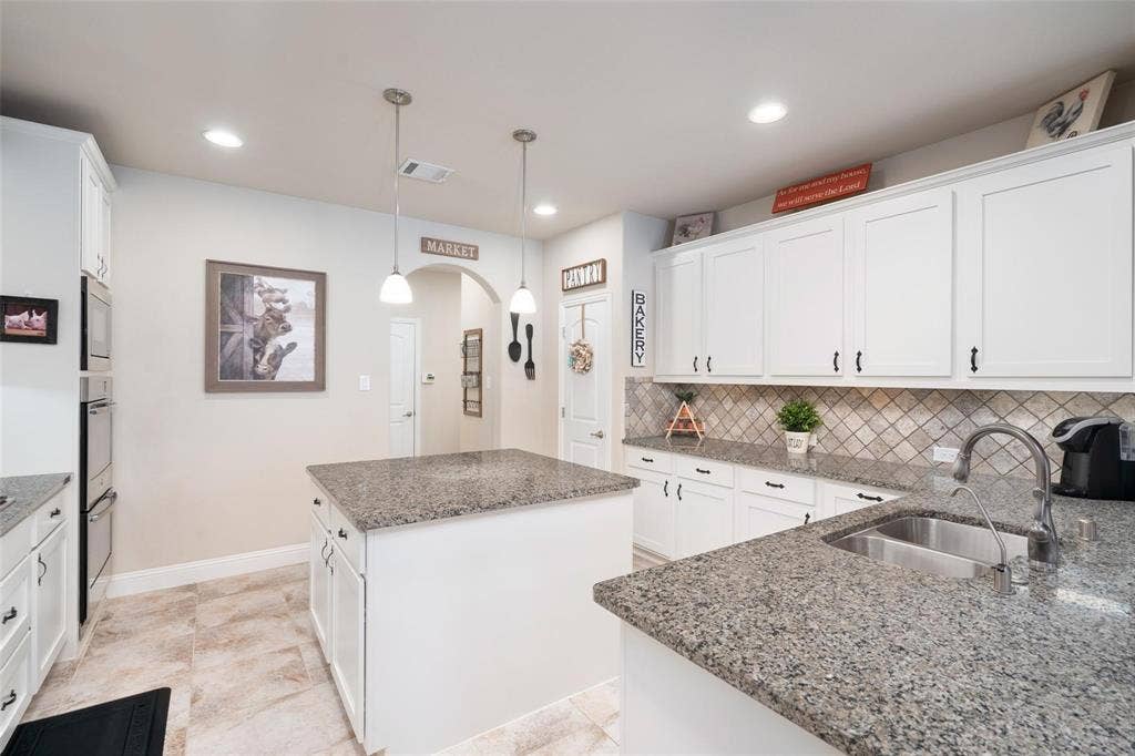 1017 Hoyt Drive, McKinney, TX 75071 Kitchen featuring a central island, double oven, white cabinetry, tile backsplash, and stone countertops