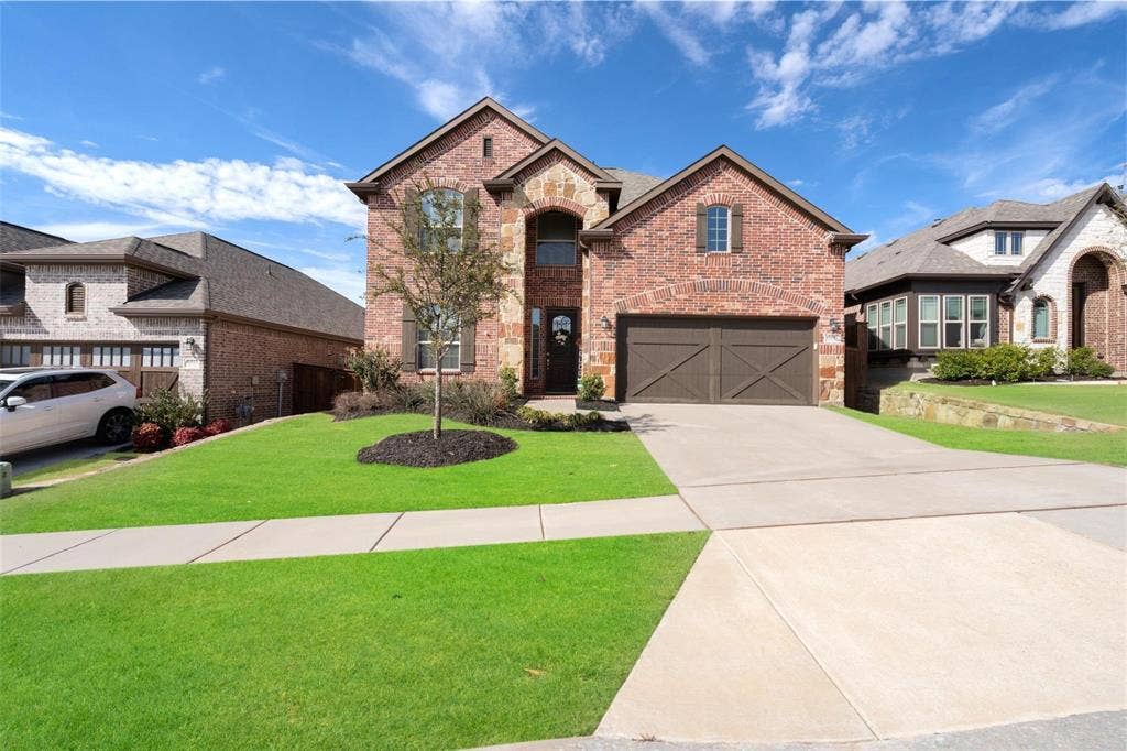 1017 Hoyt Drive, McKinney, TX 75071 Brick exterior with stone accents, arched entry, two-car garage with cross-brace doors, concrete driveway, and a front lawn