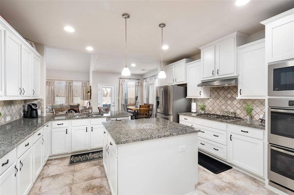 1017 Hoyt Drive, McKinney, TX 75071 White cabinetry with black hardware, granite countertops, stainless steel appliances, tile flooring, and a decorative tile backsplash