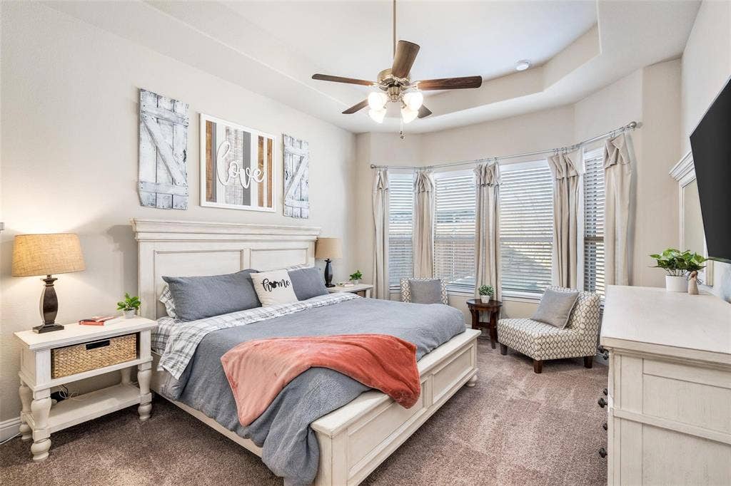 1017 Hoyt Drive, McKinney, TX 75071 Tray ceiling with a ceiling fan, bay window with blinds and drapes, and carpeted flooring