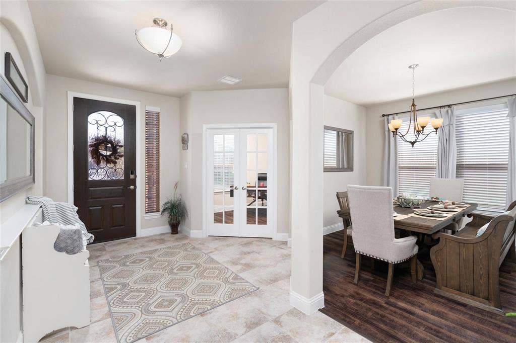 1017 Hoyt Drive, McKinney, TX 75071 Arched entryway, tile flooring, dark wood entry door with ornate glass, French doors, and a dining area with wood-finish flooring