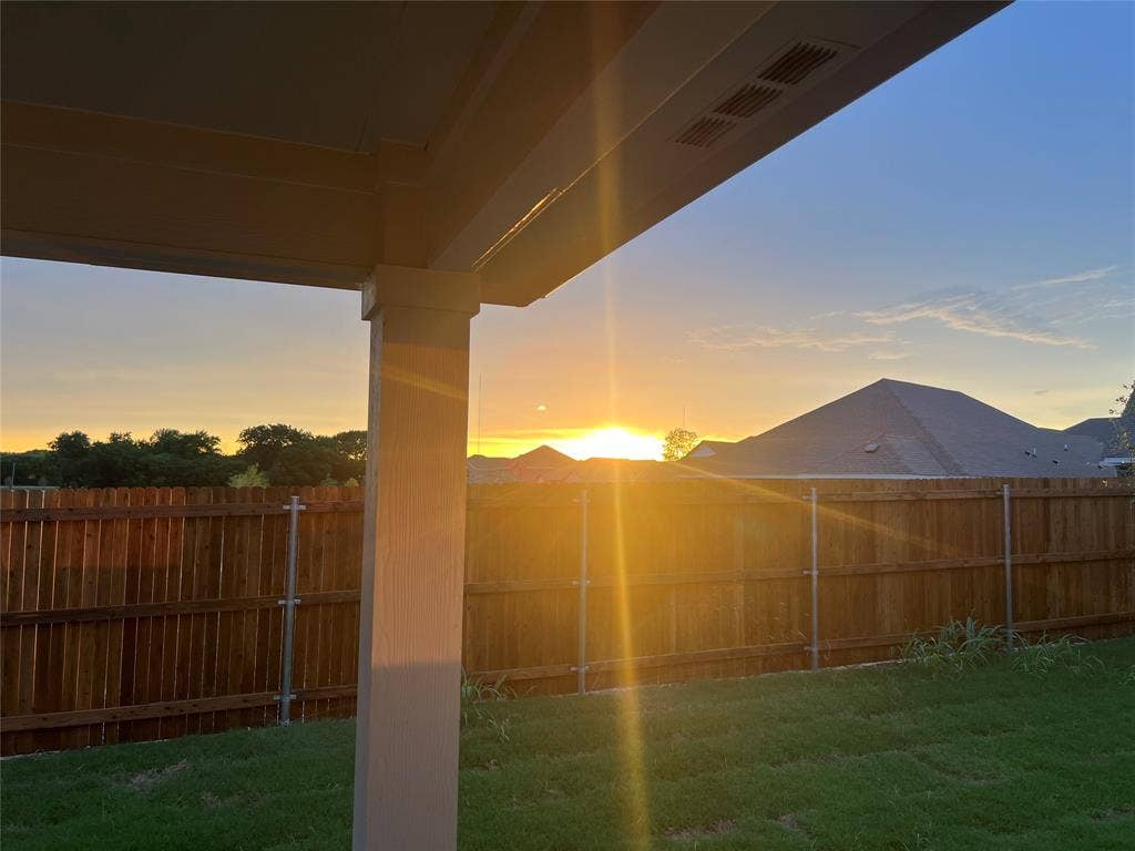 5908 Brittner Drive, Princeton, TX 75071 Covered patio with integrated lighting and expansive backyard featuring a wood privacy fence and manicured lawn