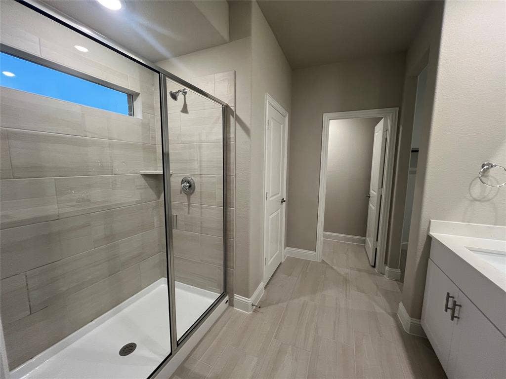 5908 Brittner Drive, Princeton, TX 75071 Glass-enclosed shower with a tiled surround, built-in shelf, and chrome fixtures