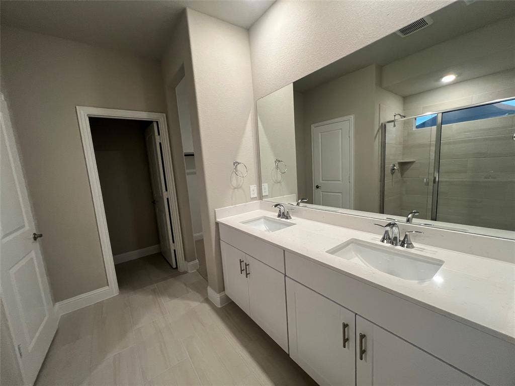 5908 Brittner Drive, Princeton, TX 75071 Dual vanity with integrated sinks, white cabinetry, and polished chrome fixtures