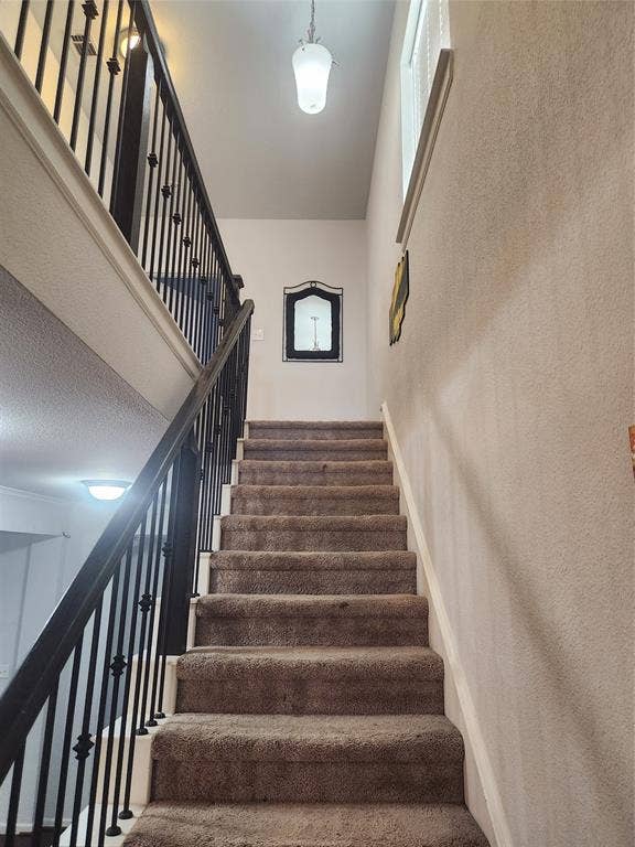 3038 Ivy Hill Lane, Irving, TX 75063 Carpeted staircase with wrought iron balusters and a pendant light fixture